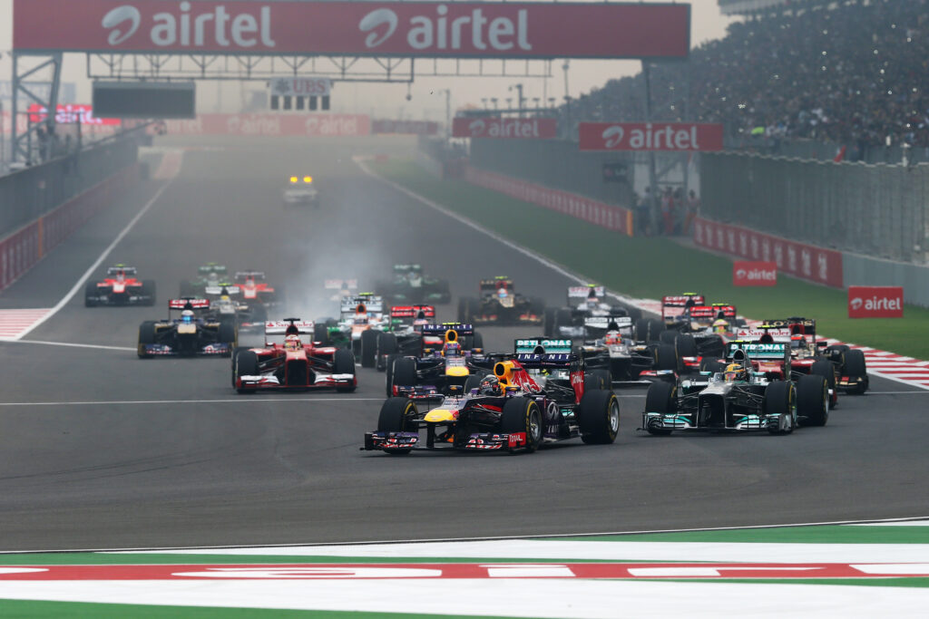 Sebastian Vettel of Red Bull Racing leads the drivers into turn one during the 2013 Indian Grand Prix
